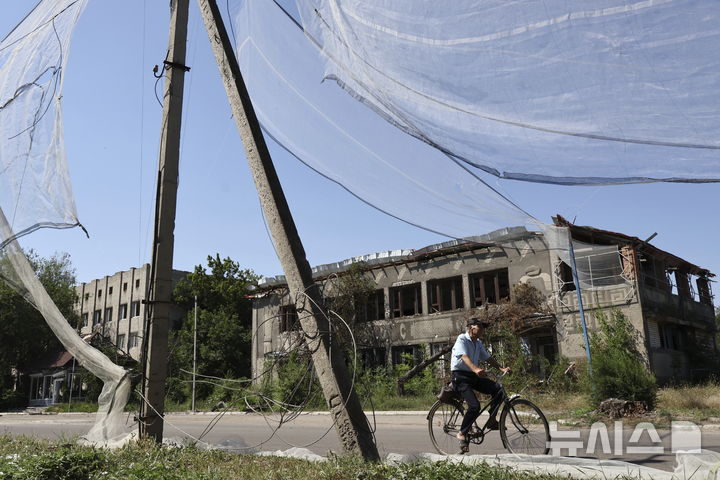 [오리히우=AP/뉴시스] 우크라이나 제65기계화여단이 제공한 사진에 15일(현지 시간) 우크라이나 자포리자주 오리히우에서 한 주민이 대(對)드론 그물이 설치된 도로를 자전거로 지나고 있다. 이 그물은 러시아의 소형 드론 공격을 효과적으로 방어하는 역할을 하고 있다. 2025.07.17.