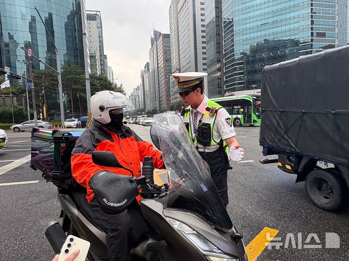 [서울=뉴시스]최은수 기자=16일 오전 서울 강남대로에서 직진 신호 전 차량 사이를 파고든 오토바이가 맨 앞까지 이동하자, 경찰이 이를 제지하고 끼어들기 금지 위반에 대해 안내하고 있다. 2025.07.16