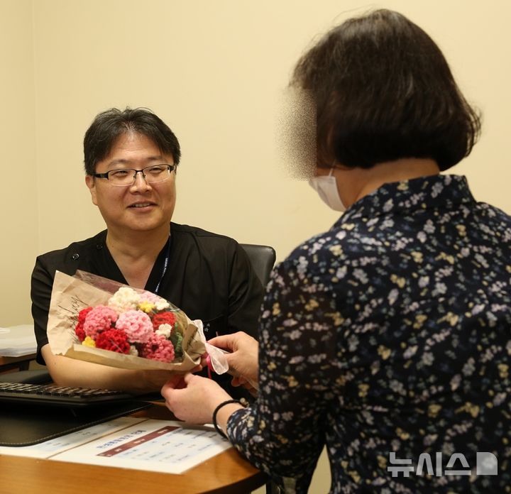 [서울=뉴시스]50대 말기 신부전 환자가 고도 감작으로 재이식이 어려운 힘든 상황을 이겨내고 두 번째 신장이식 수술로 건강을 되찾은 후 서울성모병원 신장내과 정병하 교수에게 뜨개질로 만든 카네이션 꽃다발을 전하고 있다. (사진= 서울성모병원 제공) 2025.07.17. photo@newsis.com.