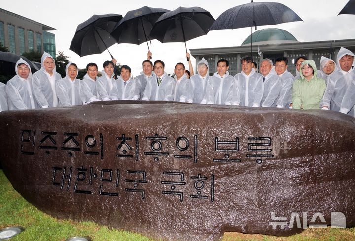 [서울=뉴시스] 국회사진기자단 = 17일 오전 서울 여의도 국회 잔디광장에서 열린 국회 상징석 제막식에서 우원식(왼쪽 여덟번째) 국회의장 등 참석자들이 기념촬영을 하고 있다. 상징석에는 국회가 민주주의의 보루로서 ‘12·3 비상계엄’ 해제를 이끌었다는 내용의 문구가 새겨져 있다. 2025.07.17. photo@newsis.com