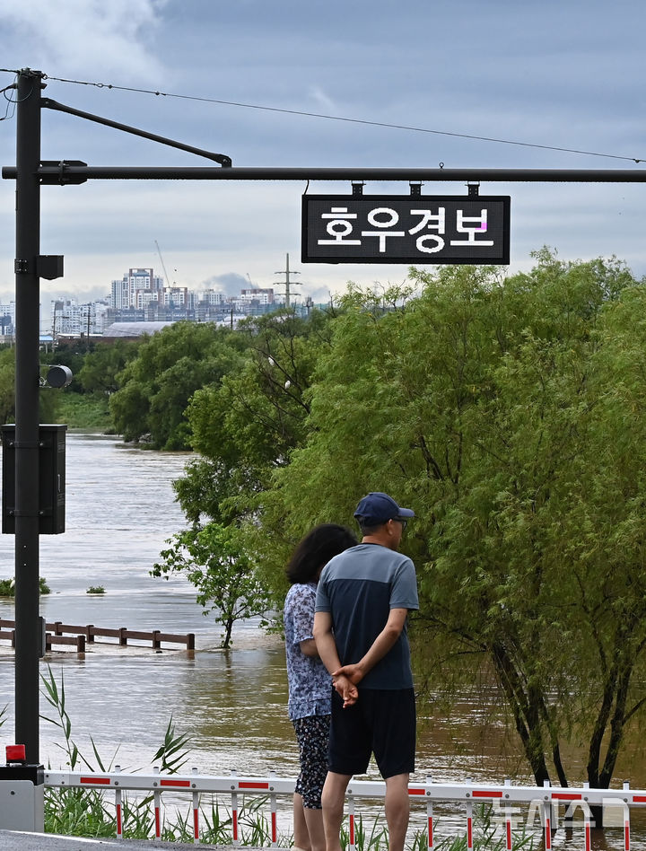 [평택=뉴시스] 김종택 기자 = 경기 남부와 충청지역에 호우경보가 발효된 17일 경기 평택시 안성천 군문교에서 시민들이 집중호우로 불어난 하천을 바라보고 있다. 2025.07.17. jtk@newsis.com
