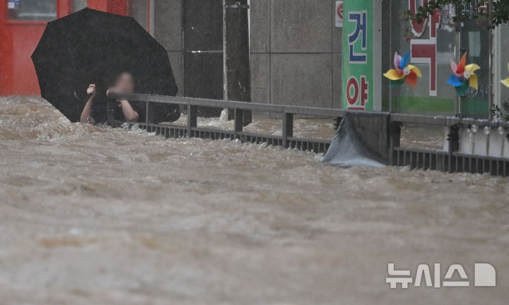 [광주=뉴시스] 이영주 기자 = 광주지역에 하루 최고 311㎜ 폭우가 쏟아진 17일 오후 침수된 광주 북구청 앞 도로에서 한 시민이 물살에 휩쓸리고 있다. 2025.07.17. leeyj2578@newsis.com