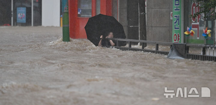 [광주=뉴시스] 이영주 기자 = 광주지역에 하루 최고 311㎜ 폭우가 쏟아진 17일 오후 침수된 광주 북구청 앞 도로에서 한 시민이 물살에 휩쓸리고 있다. 2025.07.17. leeyj2578@newsis.com