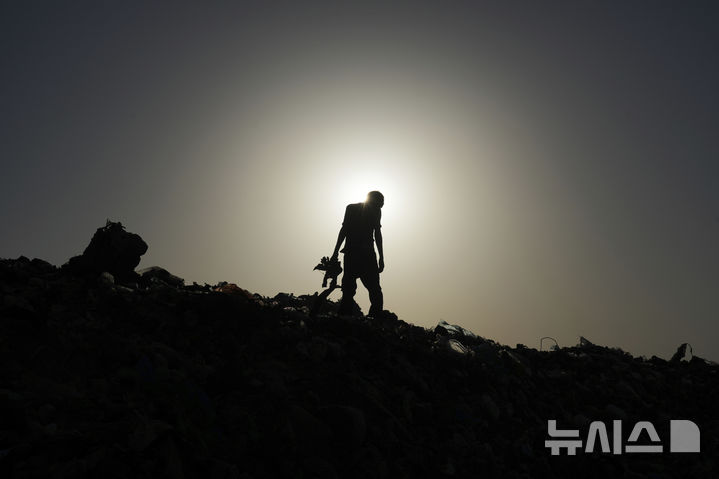 [아즈 자와이다=AP/뉴시스] 지난 17일(현지 시간) 가자지구 중부 아즈 자와이다에서 한 팔레스타인 남성이 땔감과 플라스틱, 통조림 등을 찾기 위해 쓰레기 매립지를 뒤지고 있다. 