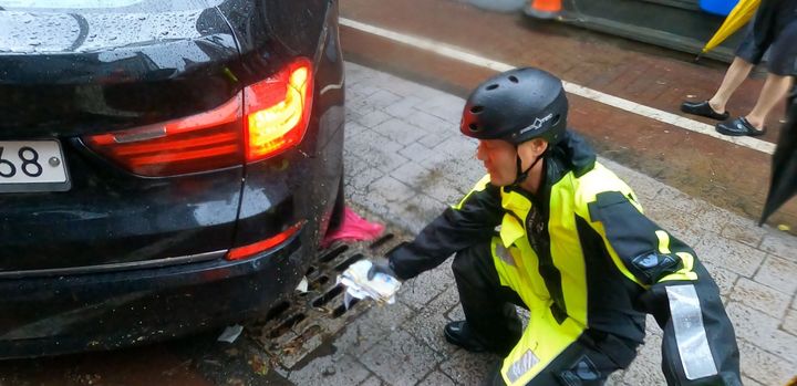 [광주=뉴시스]지난 17일 낮 12시30분께 광주 북구 중흥동 전남대학교 정문 도로에서 차량 침수 신고를 받고 출동해 배수 작업을 하던 박선홍 소방위가 유실된 돈 봉투를 발견해 수거하고 있다. (사진 = 광주 북부소방서 제공) 2025.07.18. photo@newsis.com *재판매 및 DB 금지