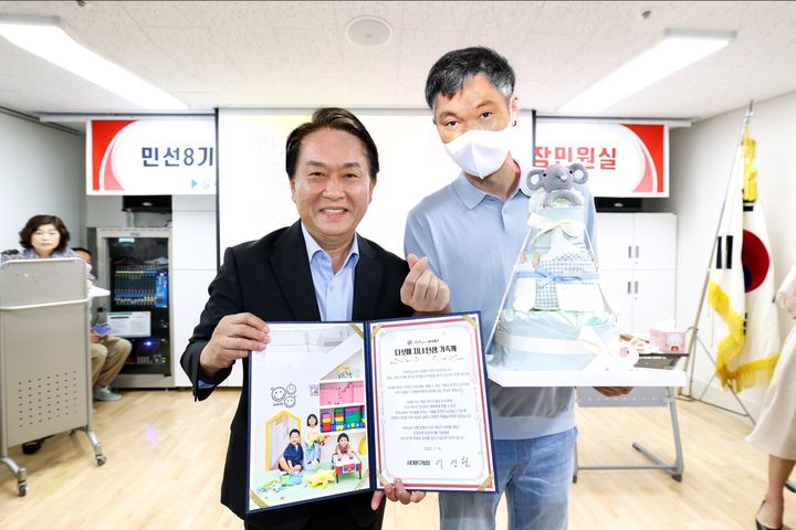 [서울=뉴시스] 이성헌 서대문구청장(왼쪽)이 이달 초 다섯째 자녀를 본 북아현동의 한 주민에게 축하 서한문과 ‘기저귀 케이크’를 전달하며 기념 촬영을 하고 있다. 2025.07.16. (사진=서대문구 제공) *재판매 및 DB 금지