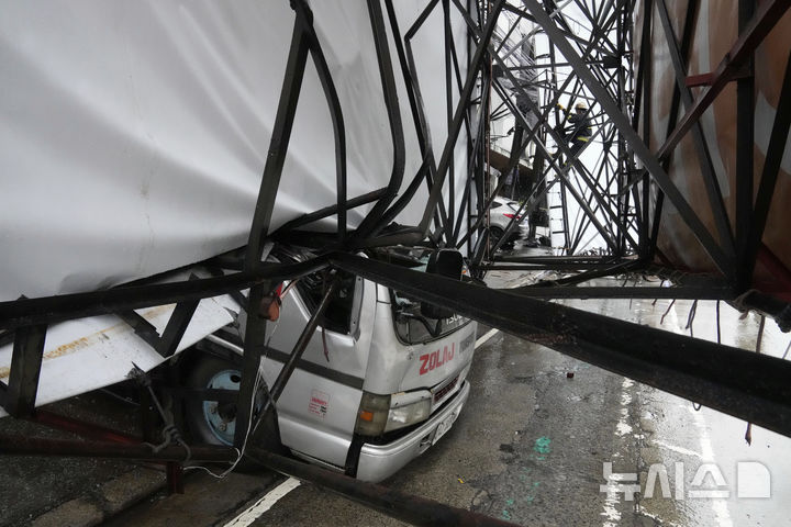 [케손=AP/뉴시스] 19일(현지 시간) 필리핀 케손시에서 제6호 태풍 위파 영향으로 광고판이 무너져 차량을 덮친 가운데 구조대원이 구조작업을 하고 있다. 2025.07.22.