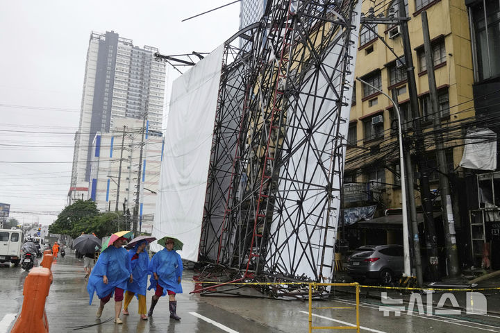 [케손=AP/뉴시스] 19일(현지 시간) 필리핀 케손시에서 제6호 태풍 위파 영향으로 구조물이 휘어진 가운데 시민들이 인근을 지나가고 있다. 2025.07.22.
