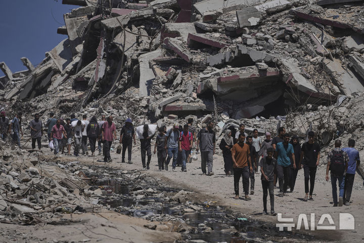 [가자지구=AP/뉴시스] 20일(현지 시간) 가자지구 북부에서 팔레스타인 주민들이 가자시티로 향하던 구호 차량 행렬에서 하역된 인도적 지원 물품을 나르고 있다. 2025.07.21.