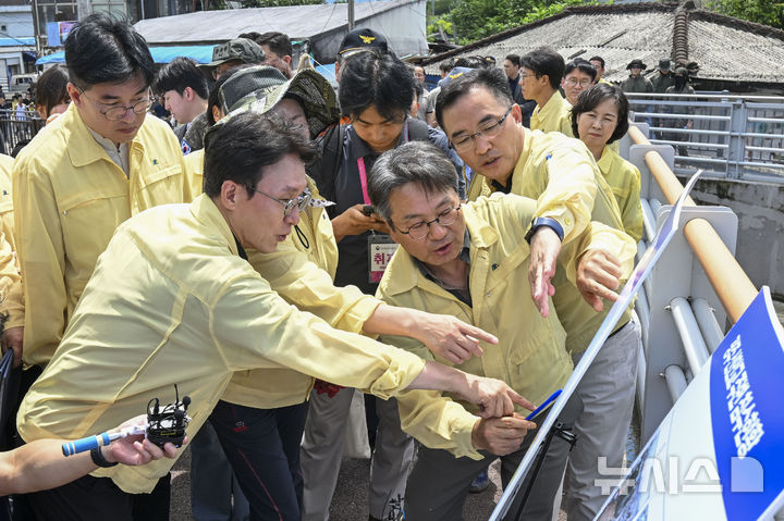 [광주=뉴시스] 이영주 기자 = 김민석 국무총리가 20일 집중호우로 침수피해를 입은 광주 북구 신안교 현장을 찾아 피해 현황을 보고받고 있다. 김 총리는 관계자들과 함께 침수 원인과 향후 복구 계획에 대해 논의하며, 주민 불편 최소화를 위한 대책 마련을 주문했다. 2025.07.20. leeyj2578@newsis.com