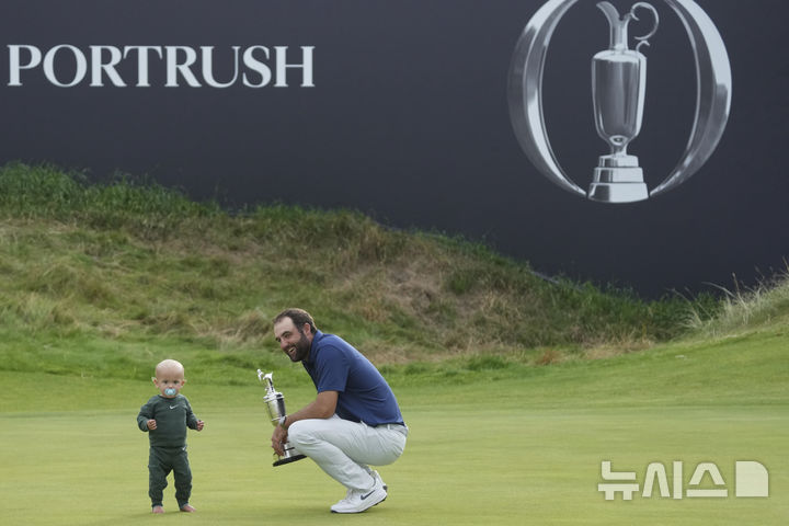 [포트러시=AP/뉴시스] 스코티 셰플러(미국)가 20일(현지 시간) 북아일랜드 포트러시의 로열 포트러시 골프클럽에서 열린 제153회 디오픈(브리티시오픈) 정상에 올라 트로피를 들고 아들 베넷과 기쁨을 나누고 있다. 셰플러는 최종 합계 17언더파 267타로 우승하며 올해 메이저 대회 두 번째 정상에 올랐다. 2025.07.21.