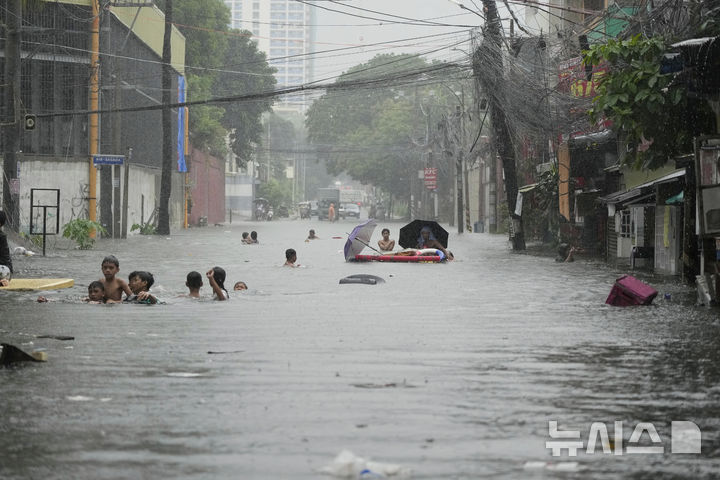 [필리핀=AP/뉴시스] 21일(현지 시간) 필리핀 케손시에서 제6호 태풍 위파 영향으로 몬순 비가 증가한 가운데 주민들이 물에 잠긴 거리를 빠져나가고 있다. 2025.07.22.