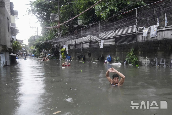 A man wades along chest-deep floods at a residential area after Tropical Storm Wipha caused intensified monsoon rains in Quezon city, Philippines, on Monday, July 21, 2025. (AP Photo/Aaron Favila)