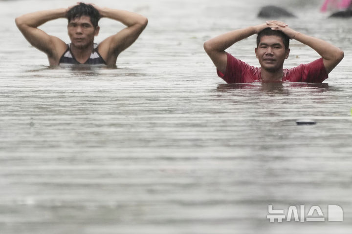 Residents wade through neck-deep floods after Tropical Storm Wipha caused intensified monsoon rains in Quezon city, Philippines, on Monday, July 21, 2025. (AP Photo/Aaron Favila)