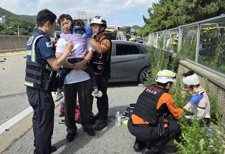 [진도=뉴시스] 지난 20일 전남 무안군 삼향읍 한 고속도로에서 교통사고 현장을 목격한 박남중 소방장이 운전자와 아이를 구조, 응급처치를 마친 뒤 119에 인계해 큰 인명피해를 막았다. 사진은 아이를 품에 안고 경찰관에게 상황 설명을 하고 있는 박 소방장. (사진 = 진도소방서 제공) 2025.07.21. photo@newsis.com *재판매 및 DB 금지