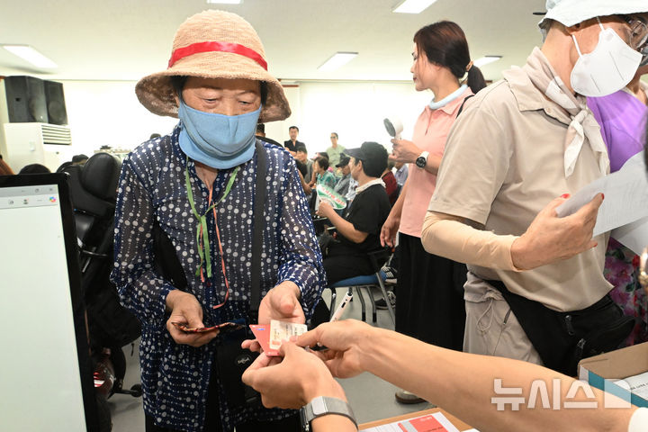 [광주=뉴시스] 이영주 기자 = 민생회복 소비쿠폰 1차 신청이 시작된 21일 오전 광주 북구 두암3동 행정복지센터에서 한 주민이 신청한 선불카드를 받고 있다. 2025.07.21. leeyj2578@newsis.com