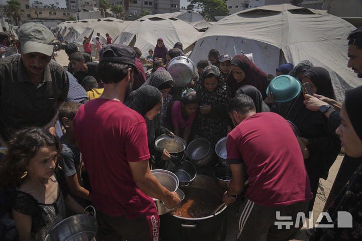 [가자시티=AP/뉴시스] 7월 말 사진으로 가자 지구 가자 시티의 난민촌에서 팔레스타인 난민들이 국제구호 조직의 배급 음식을 받고 있다. 2025.07.23.