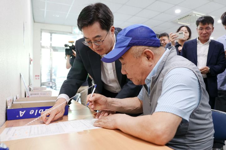 [수원=뉴시스] 김동연 경기도지사가 지난 21일 원천동 행정복지센터에서 민생회복 소비쿠폰을 신청하는 민원인을 돕고 있다. (사진=경기도 제공) 2025.07.22. photo@newsis.com *재판매 및 DB 금지