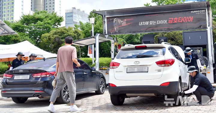 [광주=뉴시스] 이현행 기자 = 금호타이어 관계자들이 22일 오후 광주 서구 시청 야외음악당에 마련한 '자동차 타이어 무상점검 정비소'에서 시민들의 차량을 무상점검 하고 있다. 2025.07.22. lhh@newsis.com