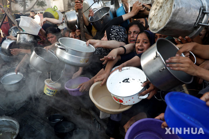 [가자시티=신화/뉴시스] 7월 20일 가자지구 가자시티 중심가에 있는 식량 배급소에 구호 음식을 받으려는 팔레스타인 주민들이 식기를 내밀며 몰려들고 있다. 가자 보건 당국은 지난 3월 이스라엘이 가자지구를 봉쇄한 이후 굶어 죽은 사람이 86명에 달하며, 이 중 76명이 어린이라고 밝혔다. 2025.08.03.