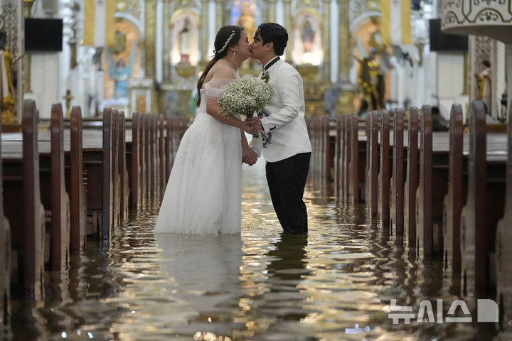 [말로로스=AP/뉴시스] 22일(현지 시간) 필리핀 불라칸 주 말로로스 바라소인 교회에서 열린 결혼식에서 신혼부부가 입맞춤을 하고 있다. 2025.07.23.