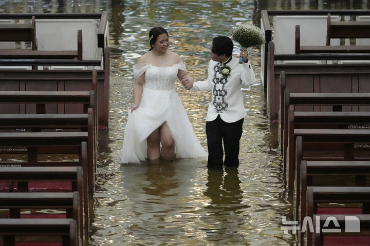 [말로로스=AP/뉴시스] 22일(현지 시간) 필리핀 불라칸 주 말로로스 바라소인 교회에서 열린 결혼식에서 신혼부부가 행진하고 있다. 2025.07.23.