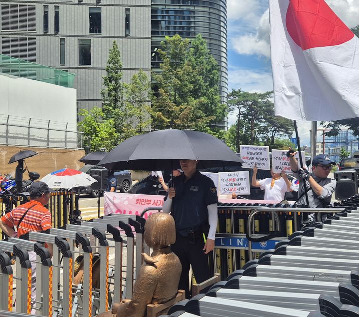 [서울=뉴시스] 이명동 기자 = 23일 오후 서울 중구 주한일본대사관 뒤편 평화의 소녀상 앞에 일본군 위안부 피해를 '사기극'으로 규정하는 보수단체 위안부법폐지국민행동 회원 등 20여 명이 정의기억연대(정의연)의 수요시위에 맞서 맞불 집회를 벌이면서 일장기를 흔들고 있다. 2025.07.23. ddingdong@newsis.com *재판매 및 DB 금지