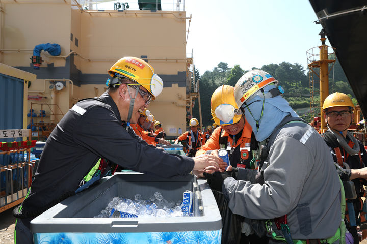 [거제=뉴시스] 신정철 기자= 한화오션 김희철 대표이사는 여름철 폭염으로 인한 현장 근로자들의 온열질환 예방을 위해 23일 거제사업장 생산 현장에서 근로자들의 휴식 공간 환경 등을 점검하고 온열질환 예방 지원 활동을 펼쳤다.사진은 김 대표(왼쪽)가 거제사업장 1도크 주변에서 근로자들에게 시원한 음료를 건네주고 있다.(사진=한화오션 제공).2025.07.23. photo@newsis.com *재판매 및 DB 금지