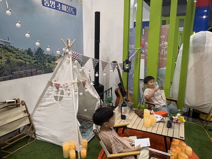 [통영=뉴시스] 신정철 기자= 경남 통영시가 ‘제10회 대한민국 국제 관광박람회’에서 지역 관광 활성화를 위한 차별화된 홍보 전략을 인정받아 마케팅 부문 최우수상을 수상했다고 23일 밝혔다. 사진은 지난 18일부터 21일까지 나흘간 경기도 일산 킨텍스에서 개최된 ‘제10회 대한민국 국제 관광박람회’에서 가족 단위 관람객들의 큰 호응을 얻은 통영시 한산면 매물도 폐교 캠핑장을 재현한 포토존 모습.(사진=통영시 제공).2025.07.23. photo@newsis.com. *재판매 및 DB 금지