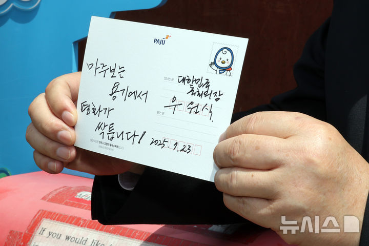 [파주=뉴시스] 국회사진기자단= 우원식 국회의장이 23일 경기도 파주 임진각 평화누리공원 통일기원 느린우체통에 '마주보는 용기에서 평화가 싹틉니다!'라고 쓴 엽서를 들어보이고 있다. 2025.07.23. photo@newsis.com