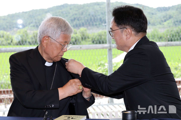 [파주=뉴시스] 국회사진기자단=우원식 국회의장이 23일 경기도 파주 임진각 평화누리공원 한 카페에서 유흥식 추기경과 대화를 하며 '진관사 태극기' 배지를 달아주고 있다. 2025.07.23. photo@newsis.com