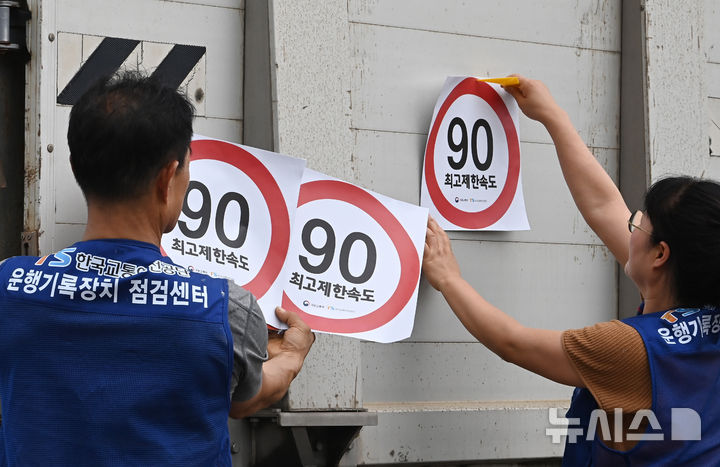 [화성=뉴시스] 김종택 기자 = 23일 경기 화성시 한 화물차 운행기록장치(DTG)점검센터에서 관계자들이 화물차 후면에 최고 제한속도 스티커를 부착하고 있다. 국토교통부와 한국교통안전공단(TS)은 오늘부터 총중량 3.5t(톤)을 초과하는 화물차를 대상으로 ‘최고 제한속도(90㎞/h) 스티커’를 부착하는 시범사업을 실시했다. 2025.07.23. jtk@newsis.com