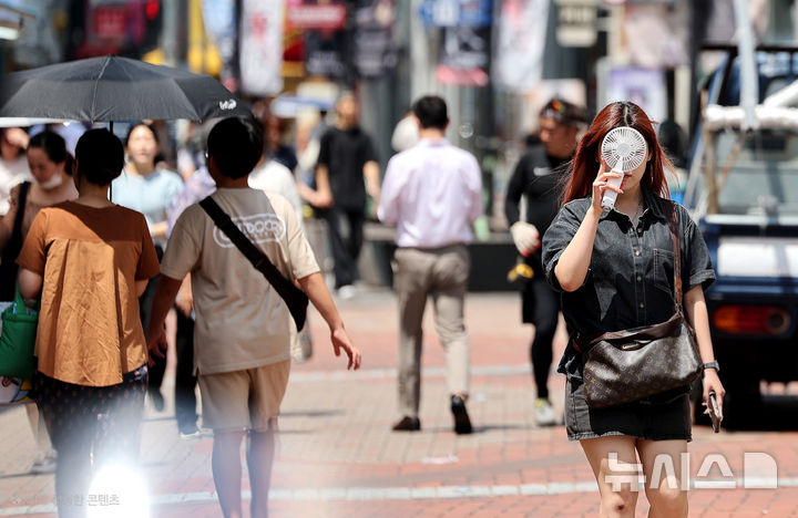 [대구=뉴시스] 이무열 기자 = 폭염이 연일 계속된 23일 대구 중구 동성로에서 한 시민이 손 선풍기를 들고 길을 걷고 있다. 2025.07.23. lmy@newsis.com
