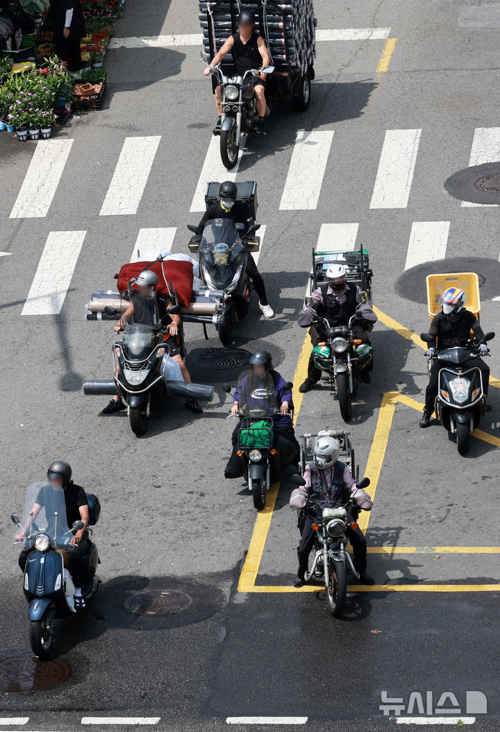 [서울=뉴시스] 이영환 기자 = 찜통 더위가 이어지고 있는 23일 오후 서울 종로구의 한 도로에서 배달업 종사자들이 달궈진 아스팔트 위에서 신호를 기다리고 있다. 2025.07.23. 20hwan@newsis.com