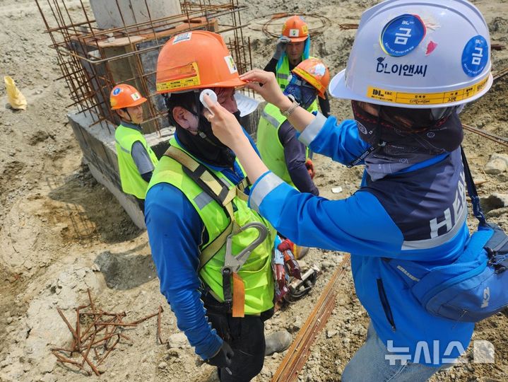[서울=뉴시스] DL이앤씨 현장 안전보건관리자가 근로자의 체온을 측정하고 건강상태를 확인하고 있다. 