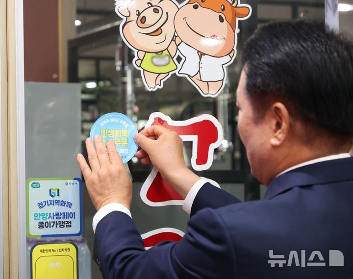 [안양=뉴시스] 최대호 시장이 직접 '민생소비 쿠폰 사용 가능 매장' 스티커를 부착하고 있다. (사진=안양시 제공).2025.07.22. photo@newsis.com *재판매 및 DB 금지
