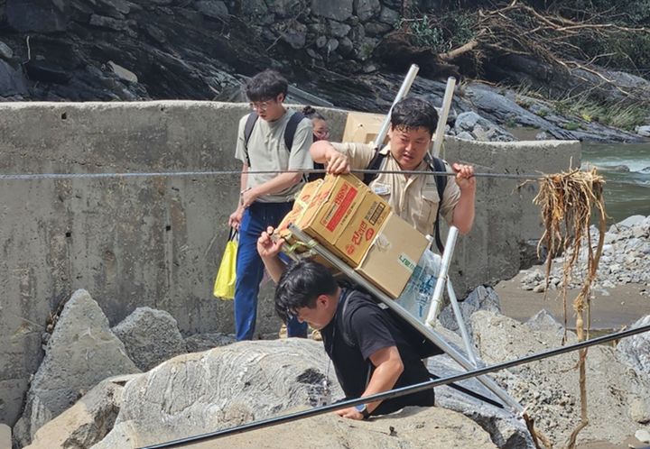 [수원=뉴시스] 경기도 연인산도립공원 소속 공무원들이 집중호우로 고립된 가평군 중산리 마을 주민들을 위해 구호물품을 지게로 나르고 있다. (사진=경기도 제공) 2025.07.25. photo@newsis.com *재판매 및 DB 금지