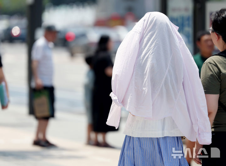 [서울=뉴시스] 김진아 기자 = 폭염이 연일 이어지고 있는 25일 서울 종로구 광화문광장 인근에서 한 시민이 옷으로 햇볕을 가리고 걸어가고 있다. 2025.07.25.bluesoda@newsis.com