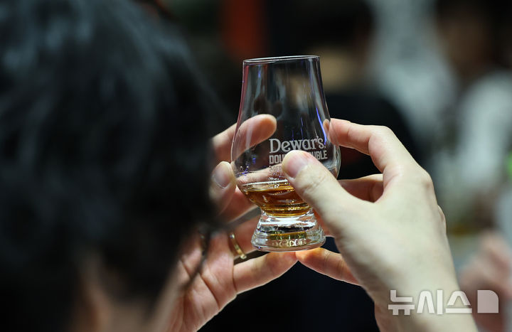 [서울=뉴시스] 22일(현지 시간) CNN, BBC 등에 따르면 짐빔은 "소비자 수요를 충족하기 위해 생산량을 평가하고 있고, 2026년 생산량을 논의했다"며 내년 1월1일부터 켄터키주 클레르몬트에 있는 제임스B.빔 단지 내 증류소 생산을 일시 중단한다고 밝혔다. 사진은 지난 7월 서울 강남구 코엑스에서 열린 '2025 서울바앤스피릿쇼'에서 한 관람객이 시음에 앞서 위스키의 상태를 살펴보는 모습. 2025.12.22.