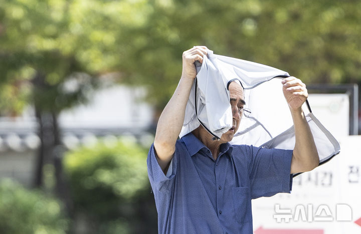 [서울=뉴시스] 김근수 기자 = 연일 이어지는 무더위 속에 26일 서울 중구 남산한옥마을을 찾은 한 관람객이 겉옷으로 햇볕을 가리며 걸어가고 있다. 2024.07.26. ks@newsis.com