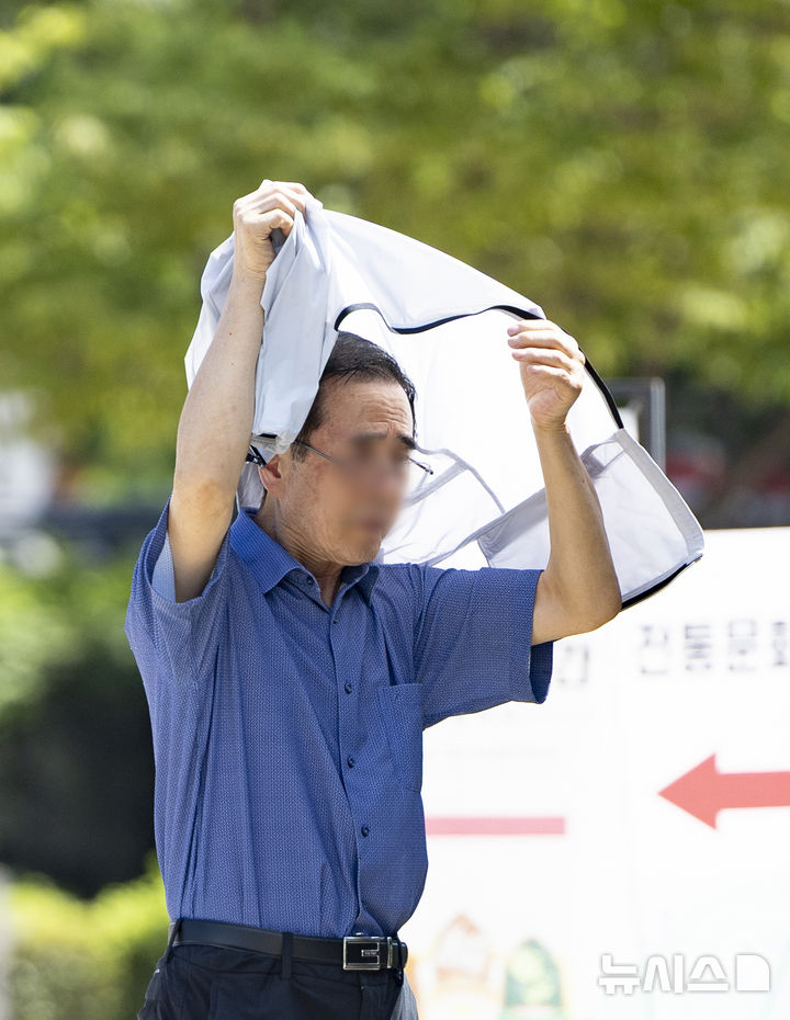 [서울=뉴시스] 김근수 기자 = 연일 이어지는 무더위 속에 26일 서울 중구 남산한옥마을을 찾은 한 관람객이 겉옷으로 햇볕을 가리며 걸어가고 있다. 2024.07.26. ks@newsis.com