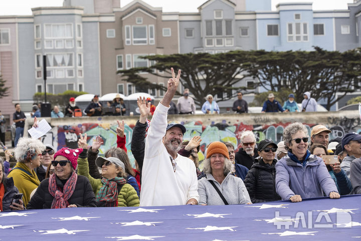 [샌프란시스코=AP/뉴시스] 2025년 7월 26일 토요일, 샌프란시스코에서 열린 '패밀리스 퍼스트(Families First)' 주최 시위에서 한 시위자가 머리 위를 나는 드론을 향해 평화의 손짓을 하고 있다. 2025.07.26.