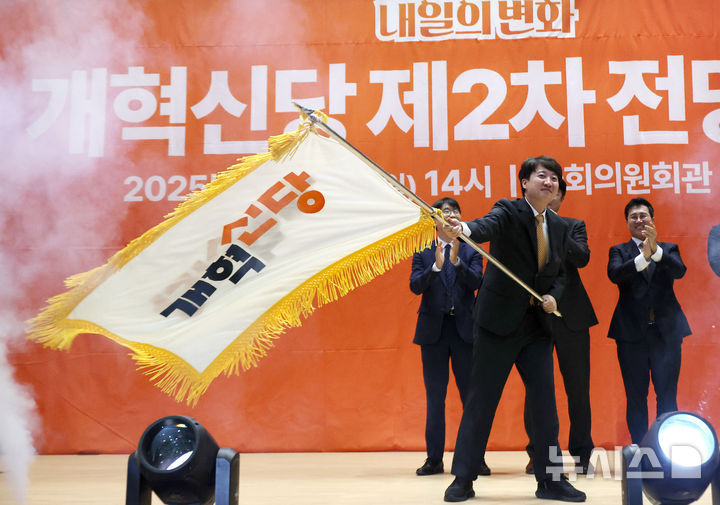 [서울=뉴시스] 김명년 기자 = 이준석 개혁신당 대표가 27일 오후 서울 여의도 국회 의원회관에서 열린 개혁신당 제2차 전당대회에서 당대표에 선출된 후 당기를 이양받아 흔들고 있다. 2025.07.27. kmn@newsis.conm