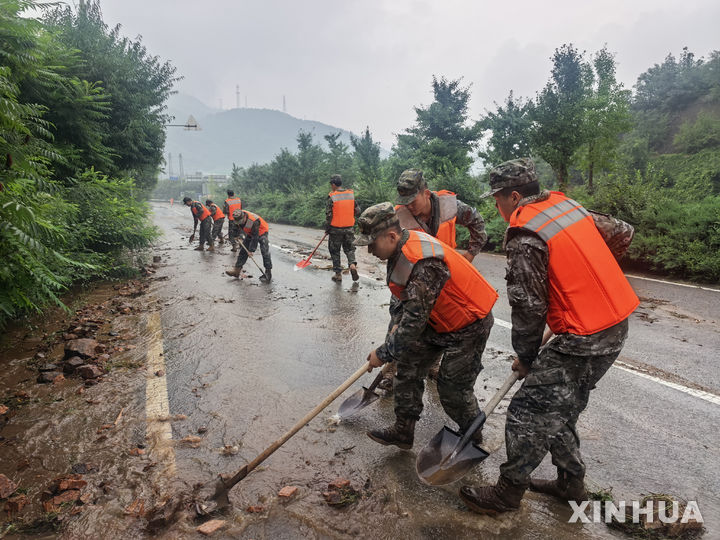 [베이징=신화/뉴시스] 중국 수도 베이징을 포함한 수도권 지역에 폭우가 이어지면서 인명피해가 발생하고 있다. 사진은 27일 베이징 미윈구의 한 마을에서 군인들이 폭우로 도로에 쌓인 토사를 치우는 모습. 2025.07.28 