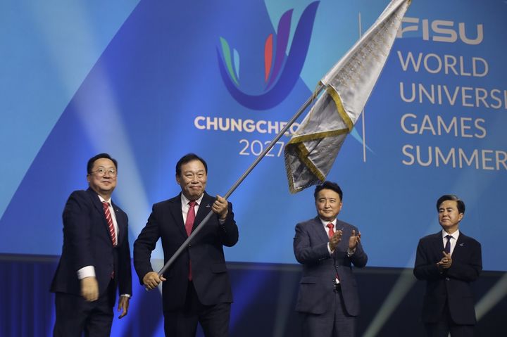 [세종=뉴시스] (왼쪽 두번째)최민호 세종시장이 충청 하계 U대회기 인수기를 받아 들고 흔들고 있다 .(사진=세종시 제공) 2025.07.28 photo@newsis.com *재판매 및 DB 금지