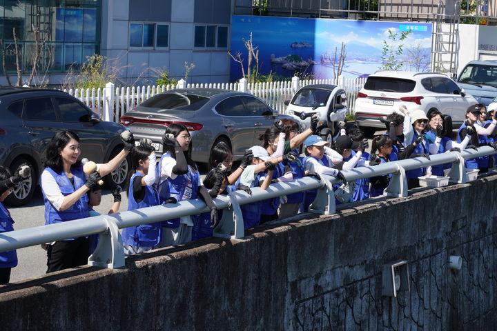 [여수=뉴시스] 여수지역 청소년 40여명이 하천 정화를 위해 연등천에 EM박테리아 흙공을 던지고 있다. (사진=LG화학 제공) 2025.07.28. photo@newsis.com *재판매 및 DB 금지