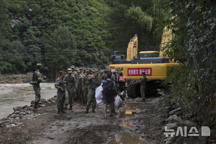 [미원=AP/뉴시스] 29일 중국 베이징 외곽 미원구에 내린 폭우로 홍수가 발생한 뒤 랑자유 마을에서 군인들이 주민들과 대화를 나누고 있다. 2025.07.29.