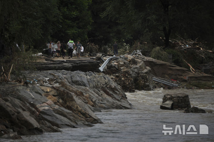 [베이징=AP/뉴시스]29일 중국 베이징 외곽 미원(密雲)구에 내린 폭우로 홍수가 발생, 주민들이 유실된 도로를 걷고 있다. 중국 수도 베이징과 인근 지방을 강타한 강력한 폭풍우가 초래한 홍수로 인한 사망자가 최소 70명으로 증가했다. 이는 31일 침수된 요양원에 갇혀 있던 노인 31명이 무더기로 숨진 채 발견된데 따른 것이다. 2025.07.31.