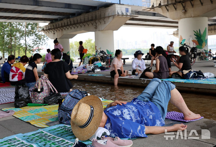 [서울=뉴시스] 이영환 기자 = 서울의 낮기온이 37도까지 오르며 폭염이 지속되고 있는 29일 오후 서울 영등포구 마포대교 남단에서 시민들이 휴식을 취하고 있다. 2025.07.29. 20hwan@newsis.com