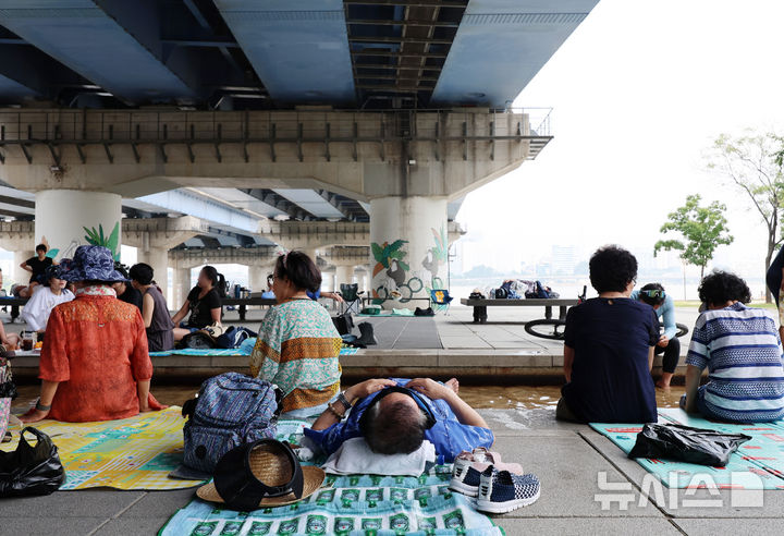 [서울=뉴시스] 이영환 기자 = 서울의 낮기온이 37도까지 오르며 폭염이 지속되고 있는 29일 오후 서울 영등포구 마포대교 남단에서 시민들이 휴식을 취하고 있다. 2025.07.29. 20hwan@newsis.com